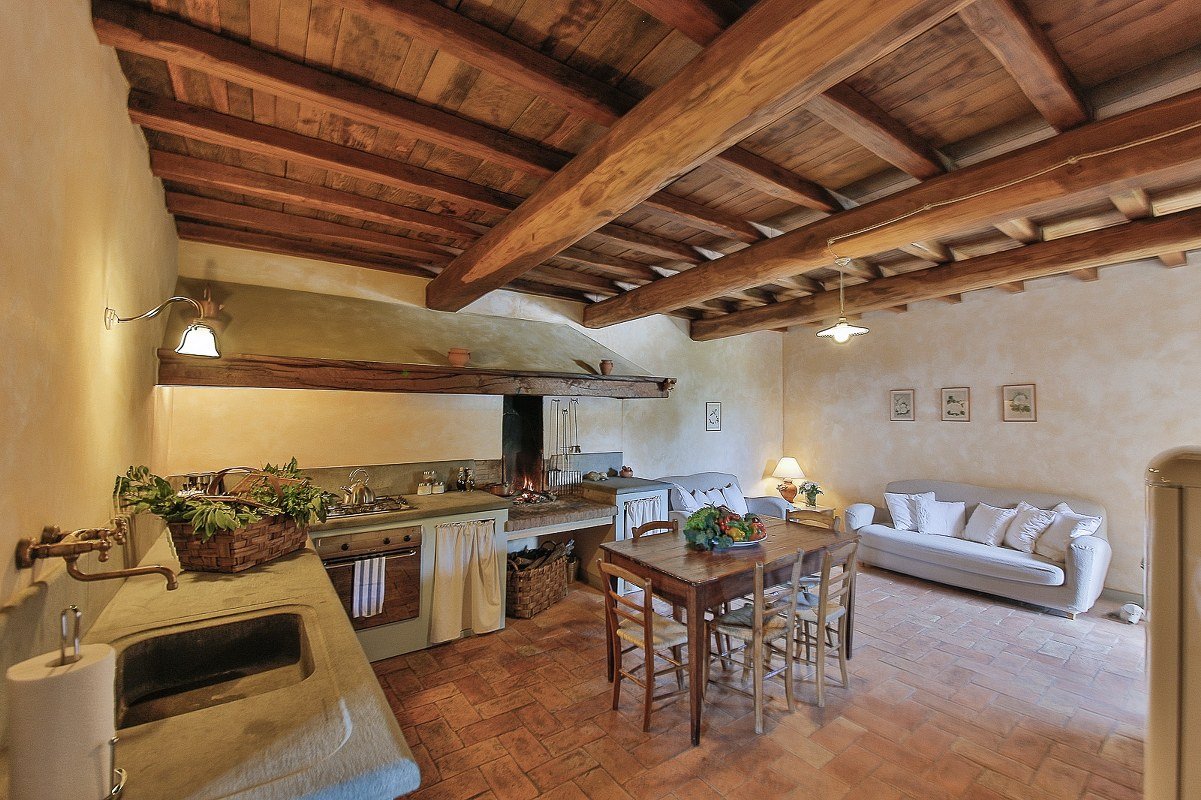 Interni di Odina con travi a vista, pavimento in cotto toscano e arredi rustici